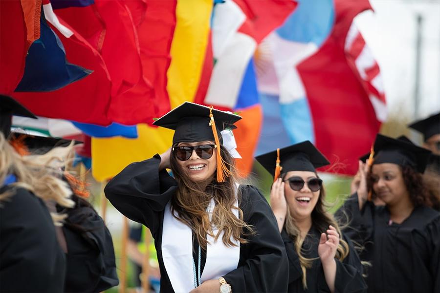 Students in graduation robes under international flags.